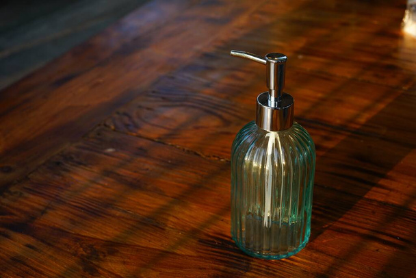 Um tiro de alto ângulo de um recipiente de sabão vazio em uma superfície de madeira capturada em um banheiro
 - Foto, Imagem
