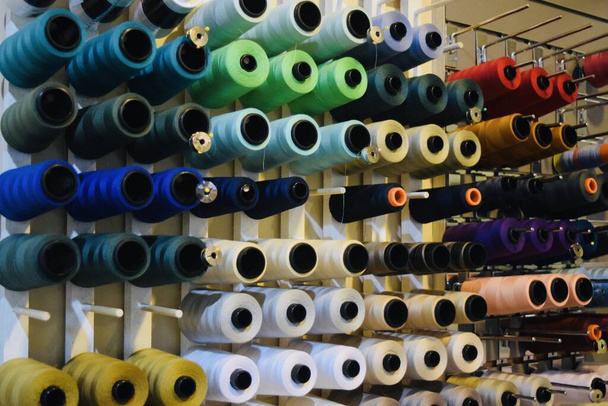 A sewing shop with colorful spools of sewing thread hanging on the wall - Photo, Image