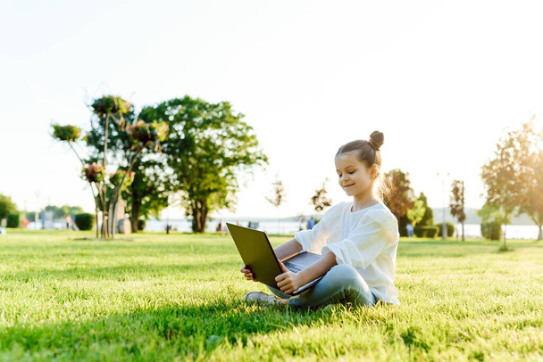 little girl play computer on green grass - 写真・画像