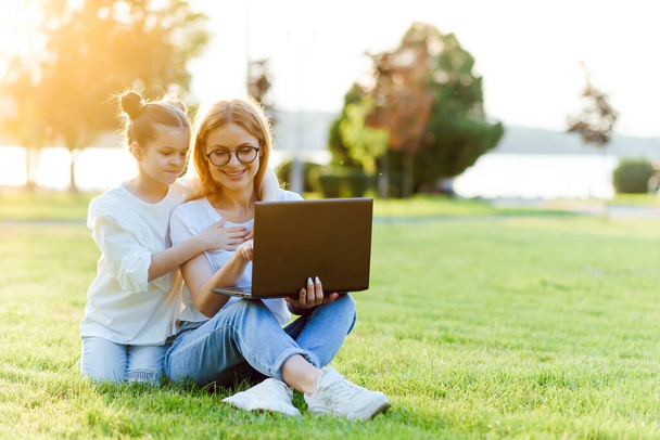 Mom and Daughter with laptop resting on meadow - Foto, Imagem