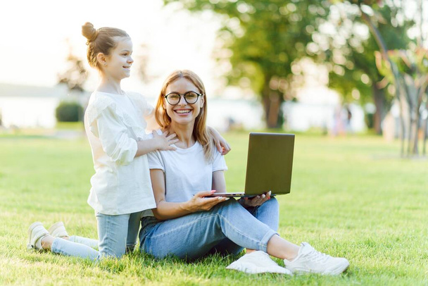 Mom and Daughter with laptop resting on meadow - Foto, Imagem