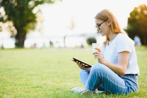 woman college student use tablet pc sit on grass - Foto, Imagen