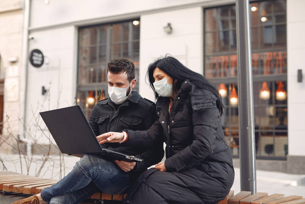 People in a masks sitting in a city with a laptop - Valokuva, kuva
