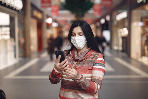 Woman in a mask stands on the street - 写真・画像