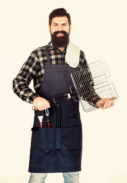 Bearded hipster wear apron for barbecue. Roasting and grilling food. Tips for cooking meat. Man hold cooking utensils barbecue. Tools for roasting meat outdoors. Picnic and barbecue. Barbecue season - Photo, image