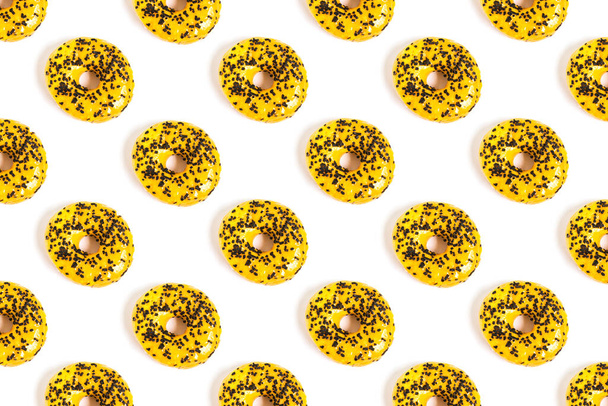 Επίπεδη μοτίβο ντόνατς σε λευκό φόντο με κίτρινο κερασάκι και σοκολάτα. Η θέα από την κορυφή. Ελάχιστη έννοια των ανθυγιεινών τροφίμων. - Φωτογραφία, εικόνα