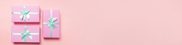 Χριστούγεννα Πρωτοχρονιά εορτασμός Αγίου Βαλεντίνου παρουσιάσει ρομαντική έννοια. Απλά ελάχιστη σχεδίαση τρία ροζ κουτί δώρου που απομονώνονται σε ροζ παστέλ πολύχρωμο φόντο. Επίπεδη lay top view αντίγραφο banner χώρο - Φωτογραφία, εικόνα