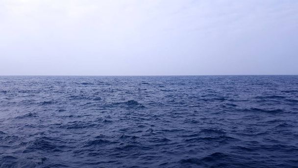 Открытая глубокая голубая океаническая вода против белого неба. Красивый морской пейзаж
. - Фото, изображение