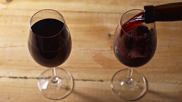 Rotwein im Glas auf hölzernem Hintergrund - Filmmaterial, Video