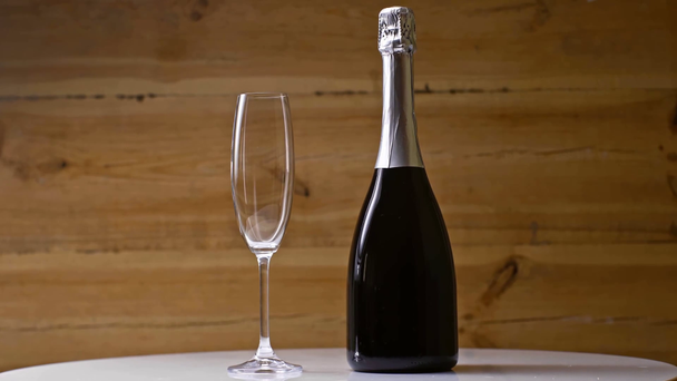 lege champagne glas in de buurt fles spinnen op houten achtergrond - Video