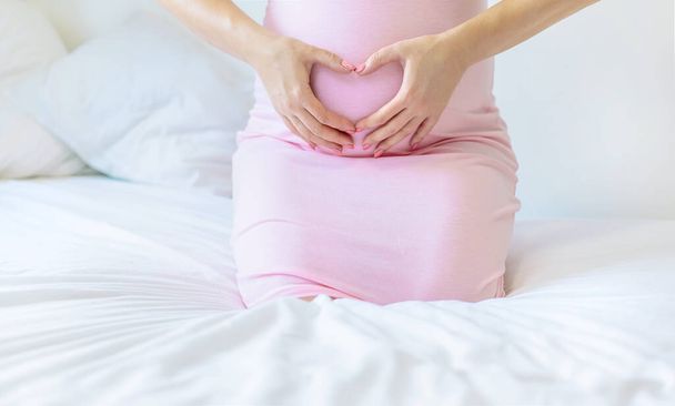 Une femme enceinte au lit lui serre le ventre. Concentration sélective. personnes. - Photo, image