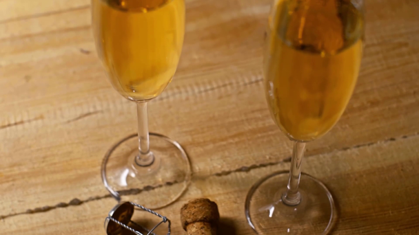 cork and champagne glasses with sparkling wine on wooden background - Footage, Video