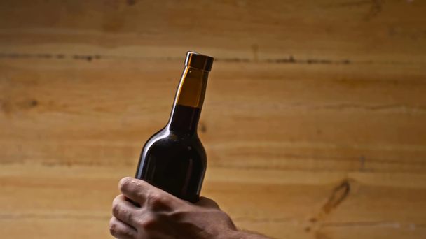 abgeschnittene Ansicht des Mannes, der eine Flasche Rotwein auf Holzgrund öffnet - Filmmaterial, Video