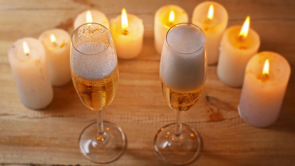 vin mousseux versant dans des verres près de bougies allumées - Séquence, vidéo