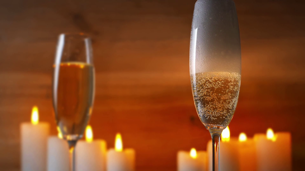 Şampanya bardağına yanan mumların yanına köpüklü şarap dökülüyor. - Video, Çekim