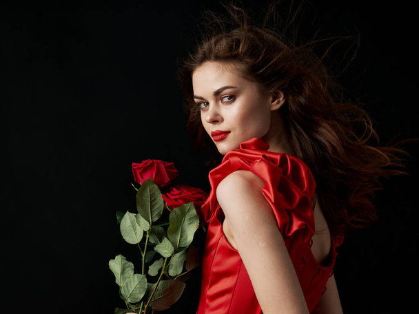 Kobieta z jasnym makijażem i w czerwonej sukience trzyma kwiat  - Zdjęcie, obraz