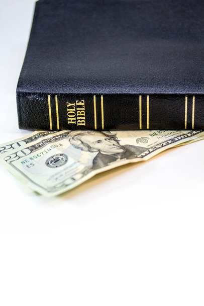 Uma bíblia cristã sagrada com uma nota de vinte dólares isolada em um fundo branco
. - Foto, Imagem
