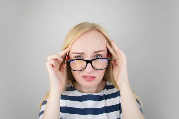 Una mujer le frota los ojos cansados con las manos sobre un fondo blanco. El concepto de fatiga ocular de la computadora y fatiga del trabajo. Dolor en los ojos y la frente, migraña, enfermedades oculares
 - Foto, imagen