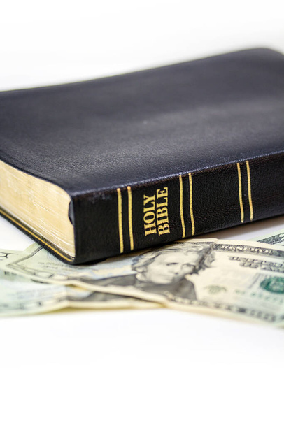 Uma bíblia cristã sagrada com uma nota de vinte dólares isolada em um fundo branco
. - Foto, Imagem