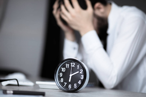 sad man with vintage clock on office des - Foto, imagen
