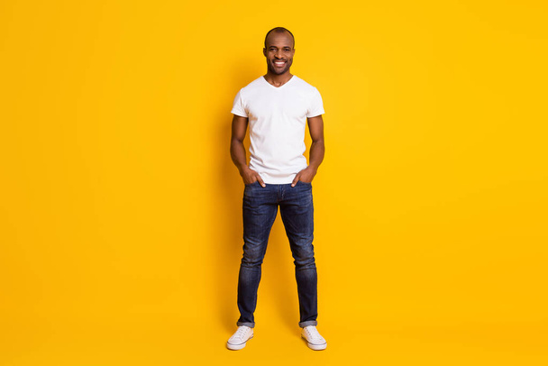 Full length body size view of his he nice attractive content cheerful cherry guy holding hands in pockets isolated over bright vivid shine vibrant yellow color background - Фото, изображение