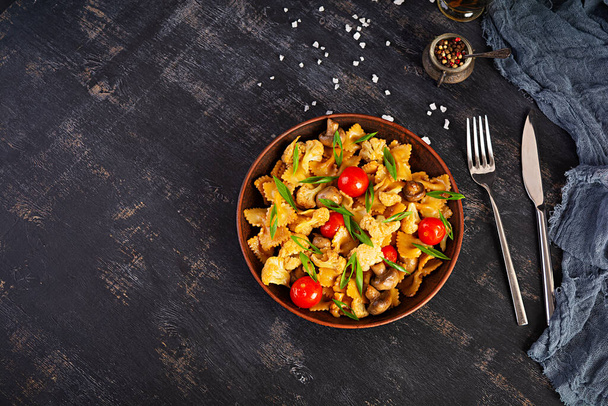 Revuelva la pasta de farfalle frita con verduras, coliflor y champiñones. Vista superior
 - Foto, imagen