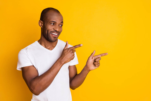 Portrait of positive cheerful afro american guy point index finger copyspace demonstrate ads promotion suggest select wear style stylish trendy clothes isolated over shine color background - Fotografie, Obrázek