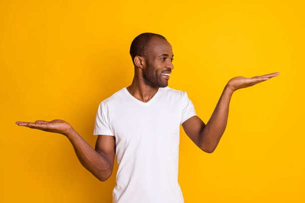 Portrait of positive afro american guy hold hand demonstrate ads promo recommend suggest select wear casual style clothes isolated over bright color background - 写真・画像