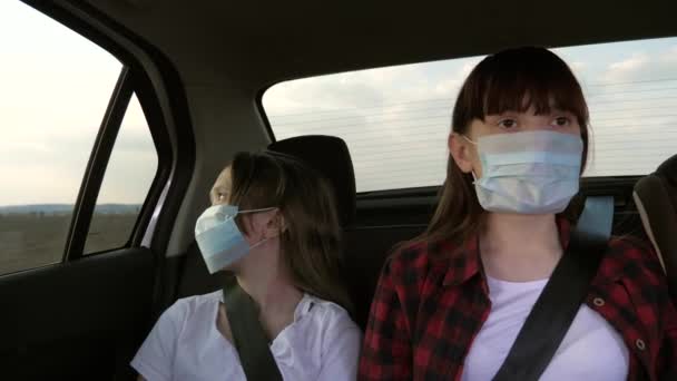 Koruyucu steril tıbbi maske takan sağlıklı genç kızlar taksiye biniyor. Salgın koronavirüs konsepti. Özgür kızlar arabada maskeli gezerler. Virüs koruması. Çocuklar arabaya biniyor. - Video, Çekim