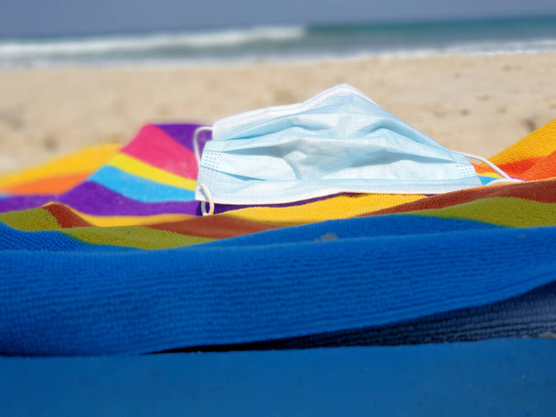 közeli arc maszk színes strand törölköző, tenger és homok a háttérben - Fotó, kép