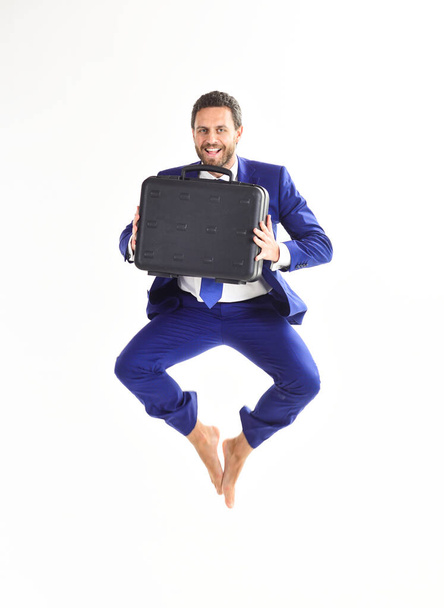 Excited business man with briefcase jumping in mid-air - 写真・画像