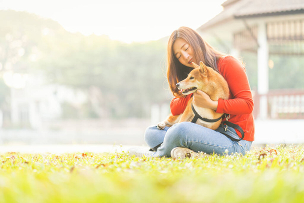 Hayvan sevici kavramı. Genç kadın ve köpek yaz konsepti. Kız arka bahçede Shiba Inu köpeğiyle oynuyor. Asyalı kadınlar köpek sipariş eder.. - Fotoğraf, Görsel