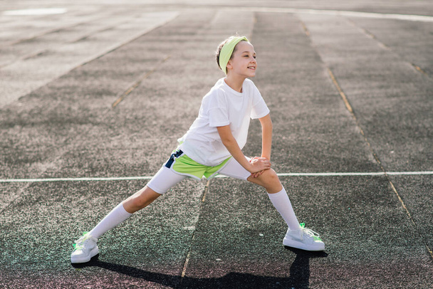 Girl jogging on a sunny summer evening, laying on treadmill, stadium, physical training, back to school, tired. - Φωτογραφία, εικόνα