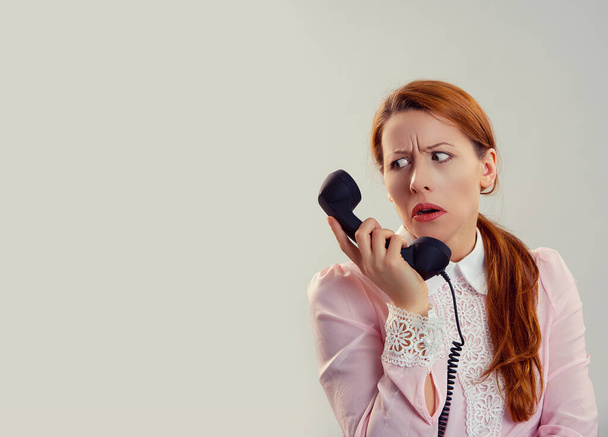 Closeup portrait cut out of a frustrated disappointed shocked beautiful woman girl looking at telephone wearing pink shirt with lace collar with hair in ponytail solated white gray background - 写真・画像