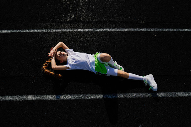 Fille jogging sur une soirée d'été ensoleillée, allongé sur tapis roulant, stade, entraînement physique, retour à l'école, fatigué. - Photo, image