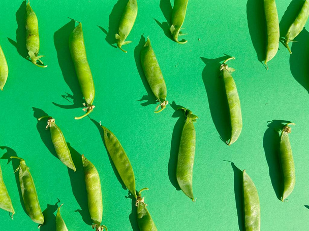 The young closed green peas lies on a bright green background - Fotoğraf, Görsel