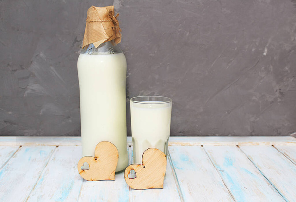 Świeże mleko w szklance i butelka na drewnianym tle. Produkty mleczarskie jako źródło wapnia. Zdrowe odżywianie - Zdjęcie, obraz