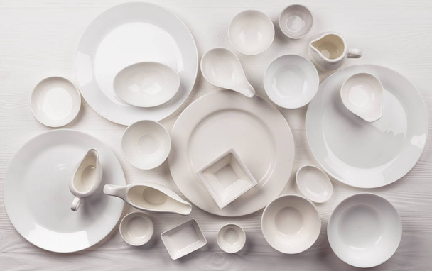 Ensemble de vaisselle vide sur fond blanc avec espace de copie, assortiment de vaisselle propre sur table en bois, vue sur le dessus - Photo, image