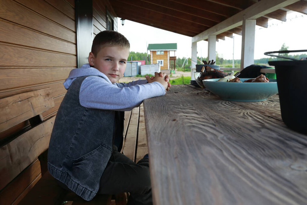 Portrait of boy has lunch on wooden terrace - Фото, зображення