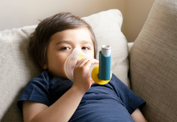 Poor boy have a problem with chest coughing holding inhaler mask, Child using the volumtic for breathing treatment, Kid having asthma allergy using the asthma inhaler, Healthcare and medicine concept - Foto, Imagen