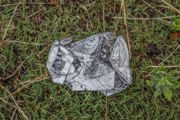 Een verweerde en verbrijzelde aluminium drankblikje dat buiten op het gras ligt en het milieu vervuilt - Foto, afbeelding