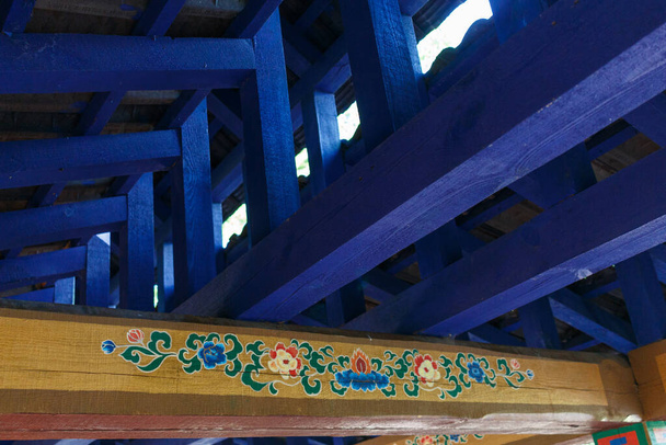 Vigas de madera azul bajo el techo de un cenador tibetano. Pisos de madera con un patrón tibetano
. - Foto, imagen