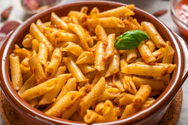 Macaroni with red pesto in a clay pan - Photo, Image