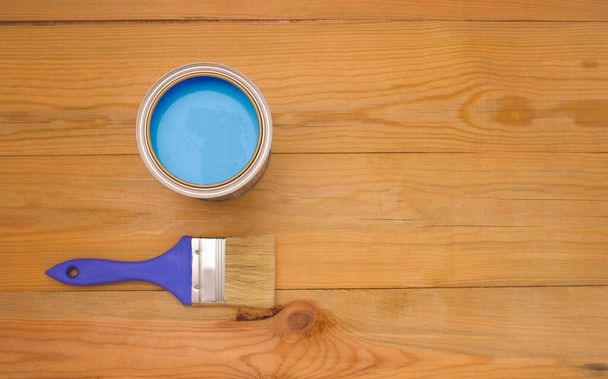 Tools for construction and decoration. Painting. A paintbrush and a metal can of paint. Wooden background, top view, copyspace. - Photo, Image