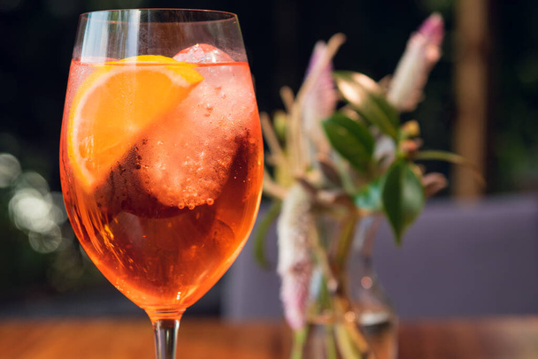 Cocktail all'arancia con guarnitura all'arancia in bicchiere di vino, spritz di mele in un ambiente soleggiato. - Foto, immagini