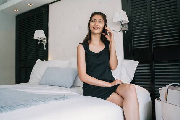 Portrait of young businesswoman talking on the phone at the hotel room. Business travel concept. - Foto, imagen