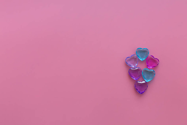 Crystal multicolored hearts on a pink horizontal background folded hearts. Valentine's day composition. Selective focus. Minimalist concept for your mockup and project. Flat lay, copy space, top view. - Foto, imagen
