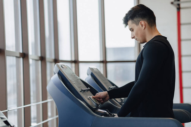 stylish guy in the gym is training on the treadmill. Healthy Lifestyle. wellness. - Zdjęcie, obraz