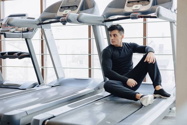 stylish guy in the gym sits resting on the treadmill. Healthy Lifestyle. wellness. - Photo, Image