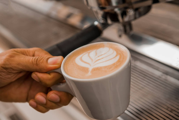 Close-up image of barista putting tamper in coffee machine when brewing drink for customer - Photo, Image